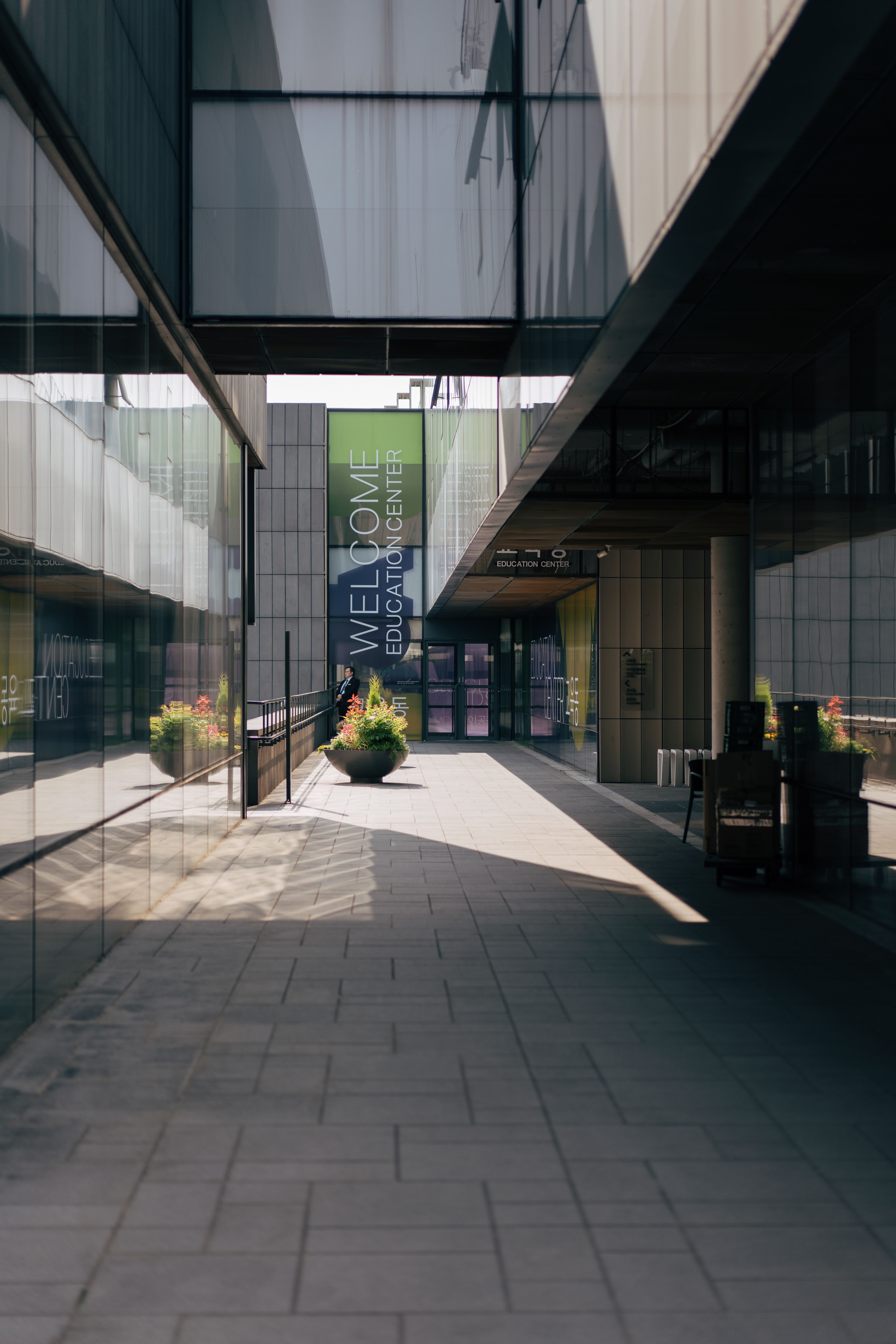 Contemporary educational center with glass reflections and walkway in urban setting.