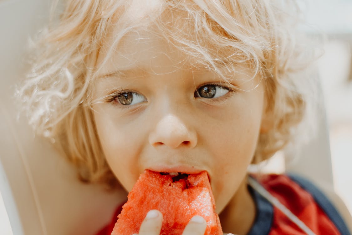 Close-Up Photo Of Boy Eating Watermelon