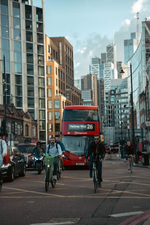 Free Cyclists navigate a bustling street in London with iconic red bus in the background. Stock Photo