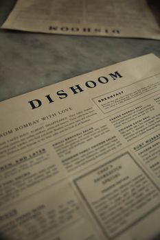 Close-up of Dishoom restaurant menu on a marble table in London, capturing its vintage style.