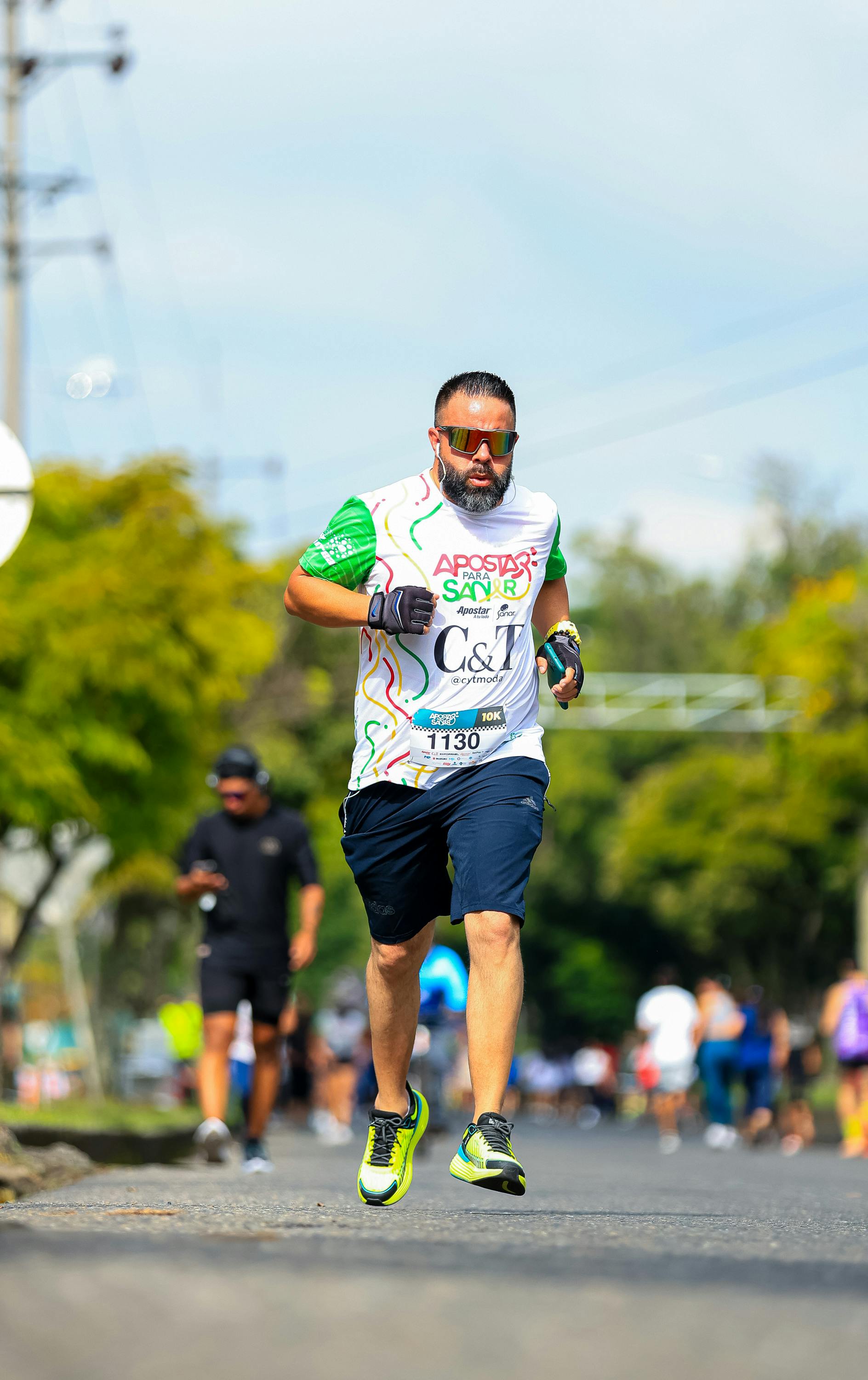 Athlete competing in a marathon outdoors wearing sports gear and sunglasses.