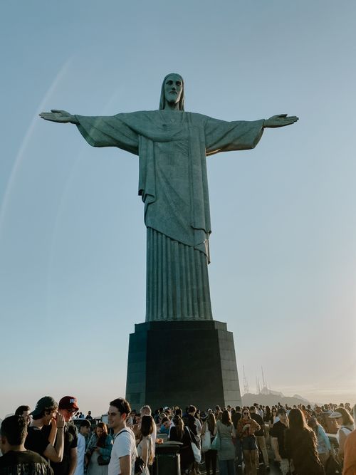 Free Christ the Redeemer statue towering over crowds at sunset in Rio de Janeiro. Stock Photo