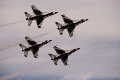 Free Four F-16 Thunderbirds perform an aerial maneuver against a cloudy sky. Stock Photo