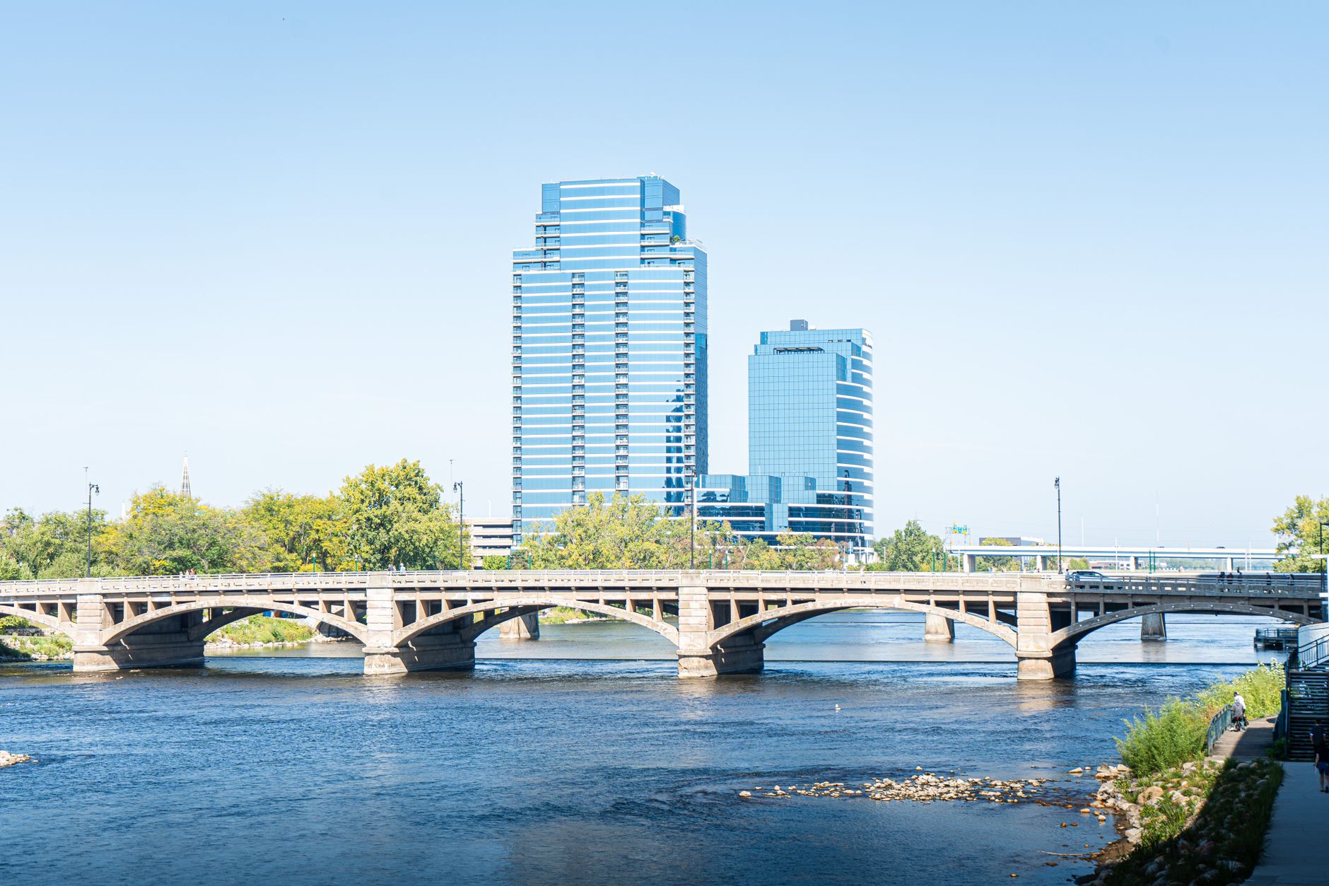 Scenic view of downtown Grand Rapids with iconic bridge and modern skyscrapers reflecting on the river.