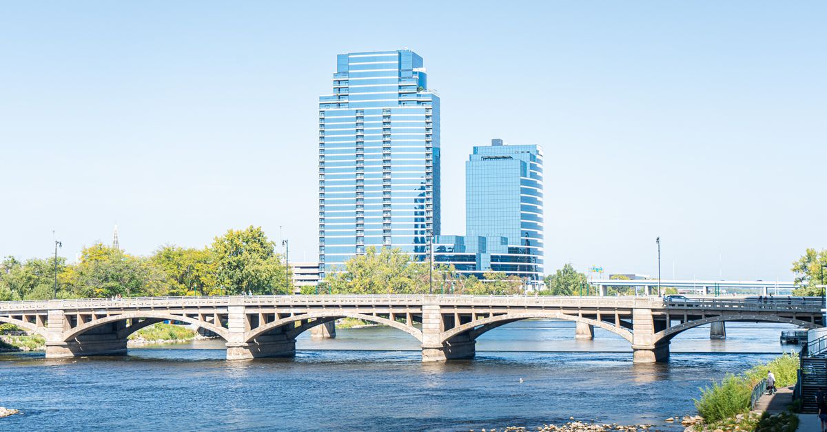 Scenic view of downtown Grand Rapids with iconic bridge and modern skyscrapers reflecting on the river.
