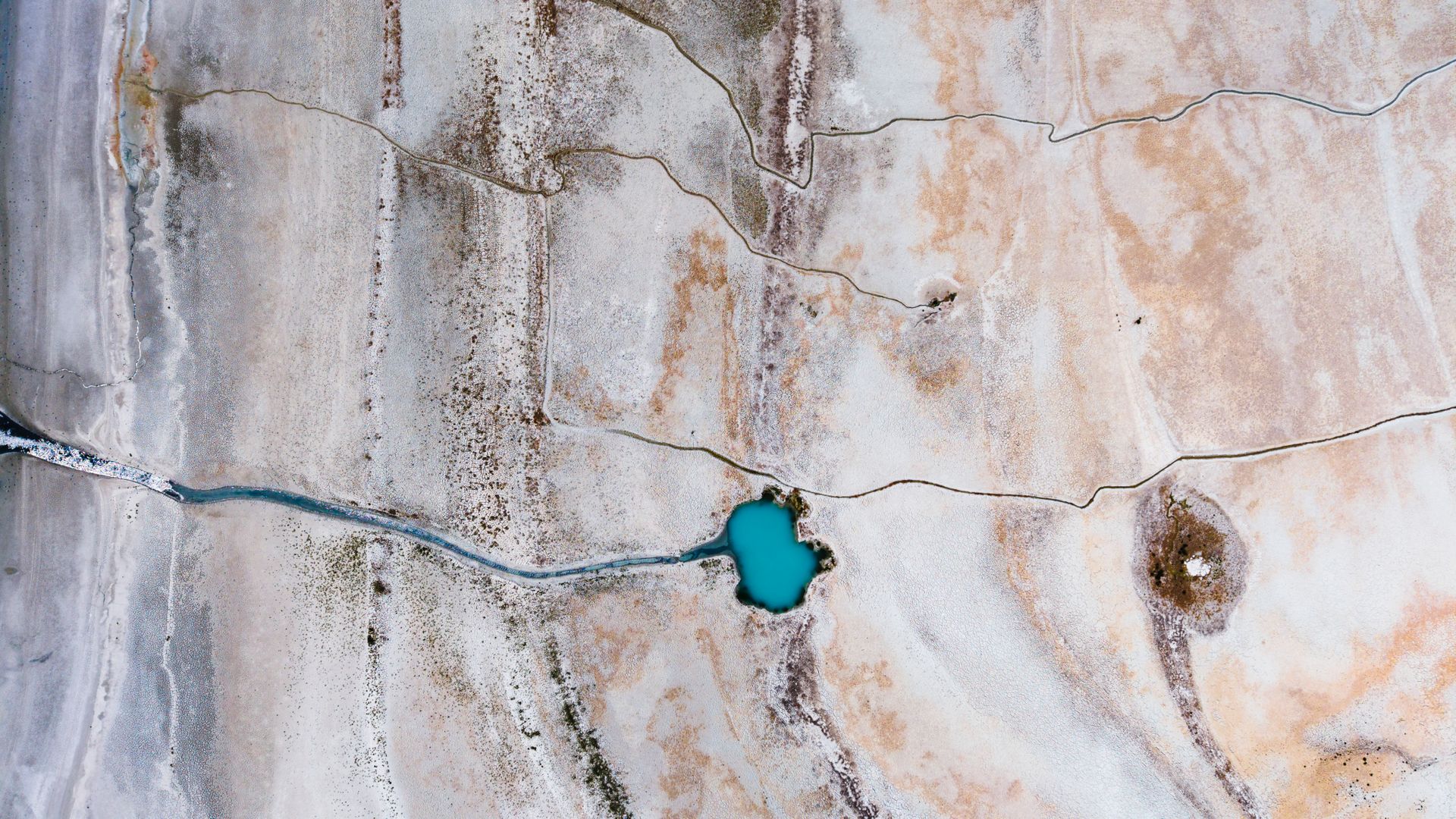 A stunning aerial view capturing a mineral-rich lake surrounded by textured landscape in Türkiye.