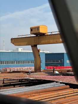 Industrial scene with a yellow crane and workers at Tianjin Port, China.