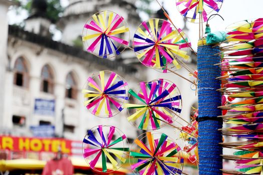 Vibrant pinwheels spinning in a lively street market backdrop.