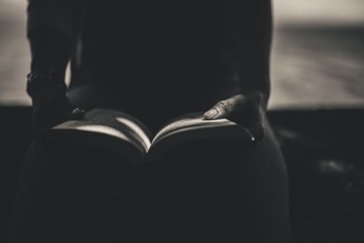 Silhouetted hands holding a book, creating a mysterious reading ambiance.