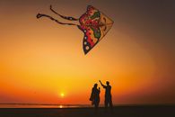 A couple flies a colorful kite at sunset on Cox's Bazar beach, Bangladesh.