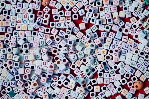 Free A vibrant assortment of alphabet beads spread across a red surface, showcasing creativity and education. Stock Photo