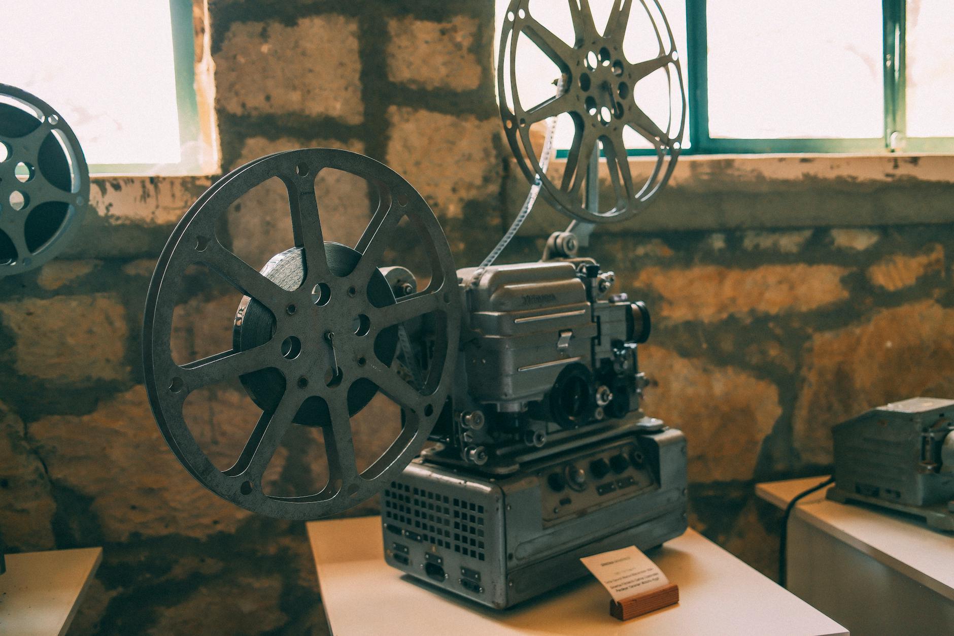 Sinema kelimesinin tarihsel kökenini ve sinemanın geçmişini temsil eden antika bir film projektörü ve film şeritleri.