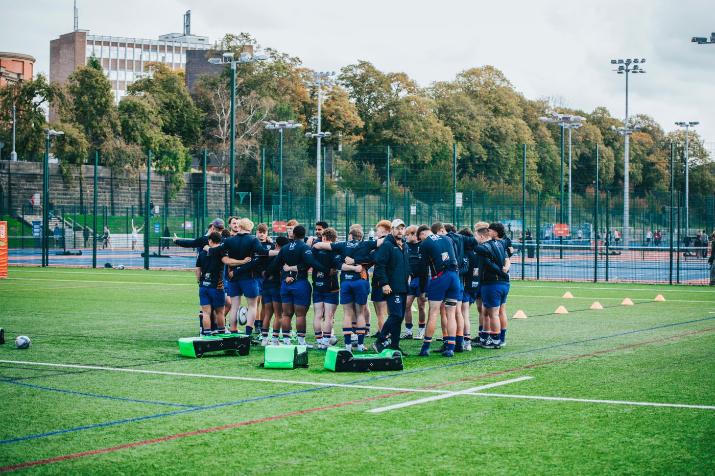 Rugby team gathered with its coach during an outdoor training session