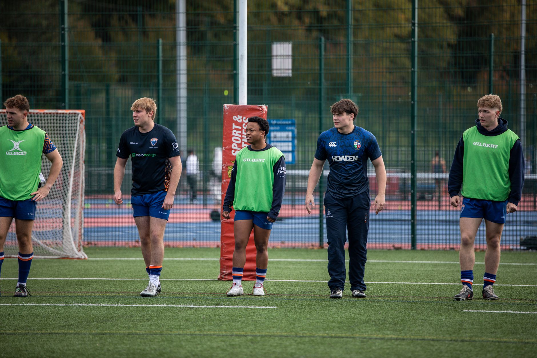 Group of young rugby players training outdoors on a grass field.