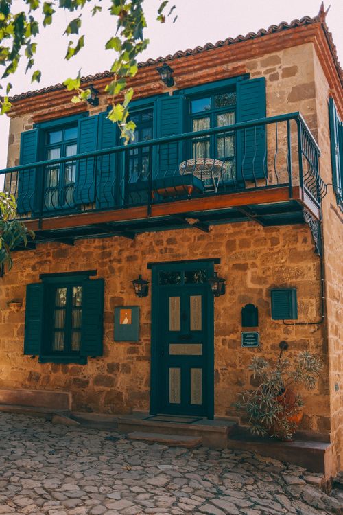Free Rustic stone house with vibrant blue shutters and balcony. Quaint and charming architectural detail. Stock Photo