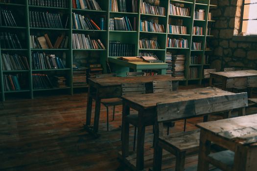 A rustic, vintage classroom featuring wooden desks and bookshelves filled with books.