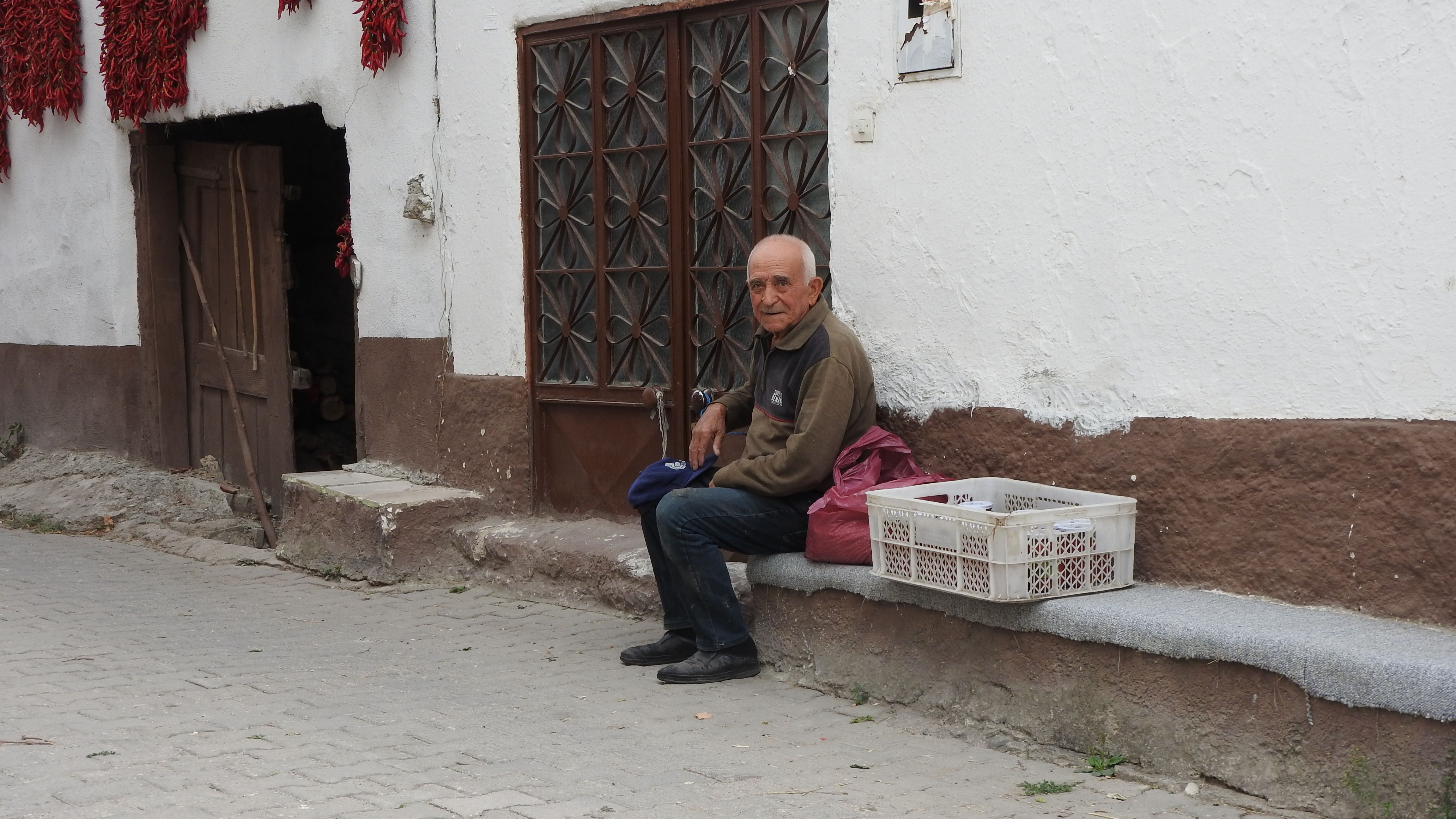 Elderly Man Relaxing by Rustic House Exterior · Free Stock Photo