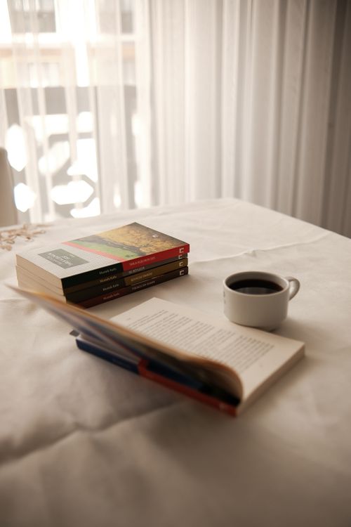 Free Warm indoor scene with open book, stacked books, and coffee on table. Stock Photo