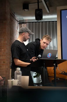 Two men collaborating during a presentation at an indoor conference setting.