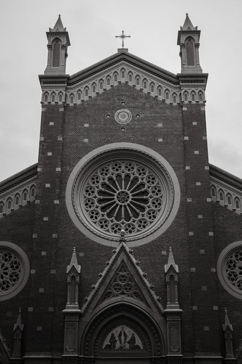 Free A black and white photo of a Gothic church facade featuring detailed circular stained glass windows. Stock Photo