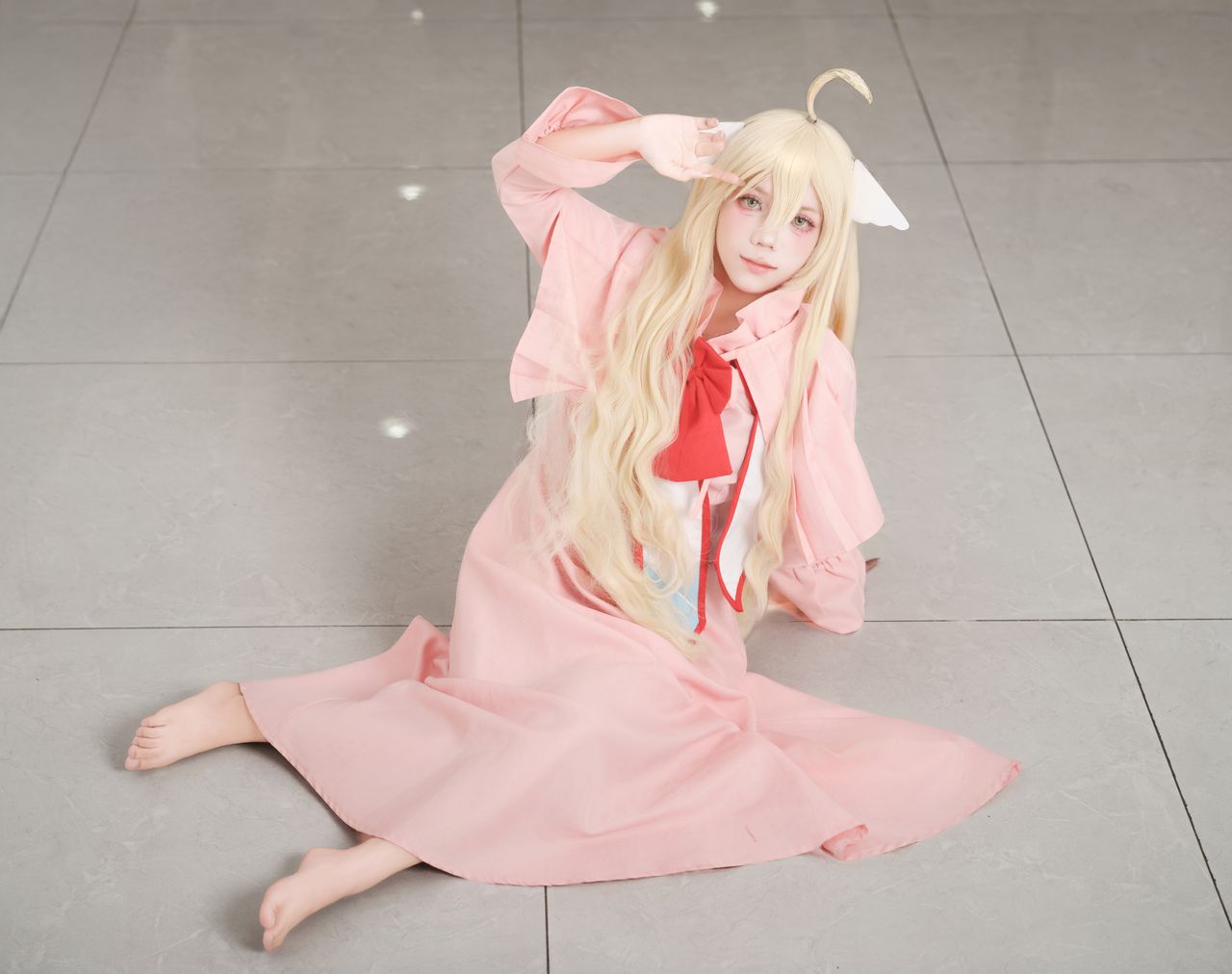 cosplay character sitting indoors in a pink dress with a playful pose