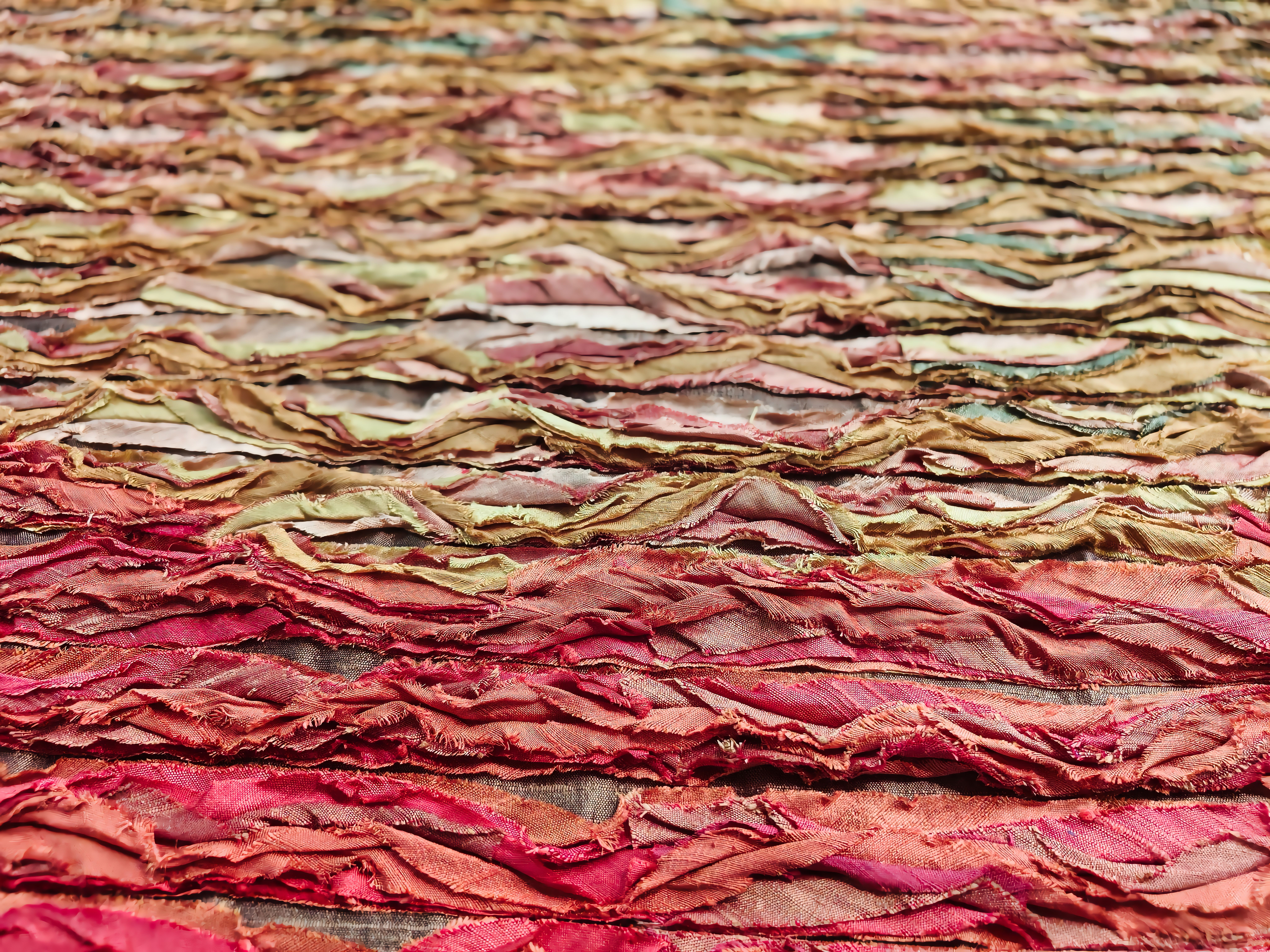 Close-up view of a colorful, textured fabric surface with layers of vibrant reds and browns. — Maynard Longarm Quilting