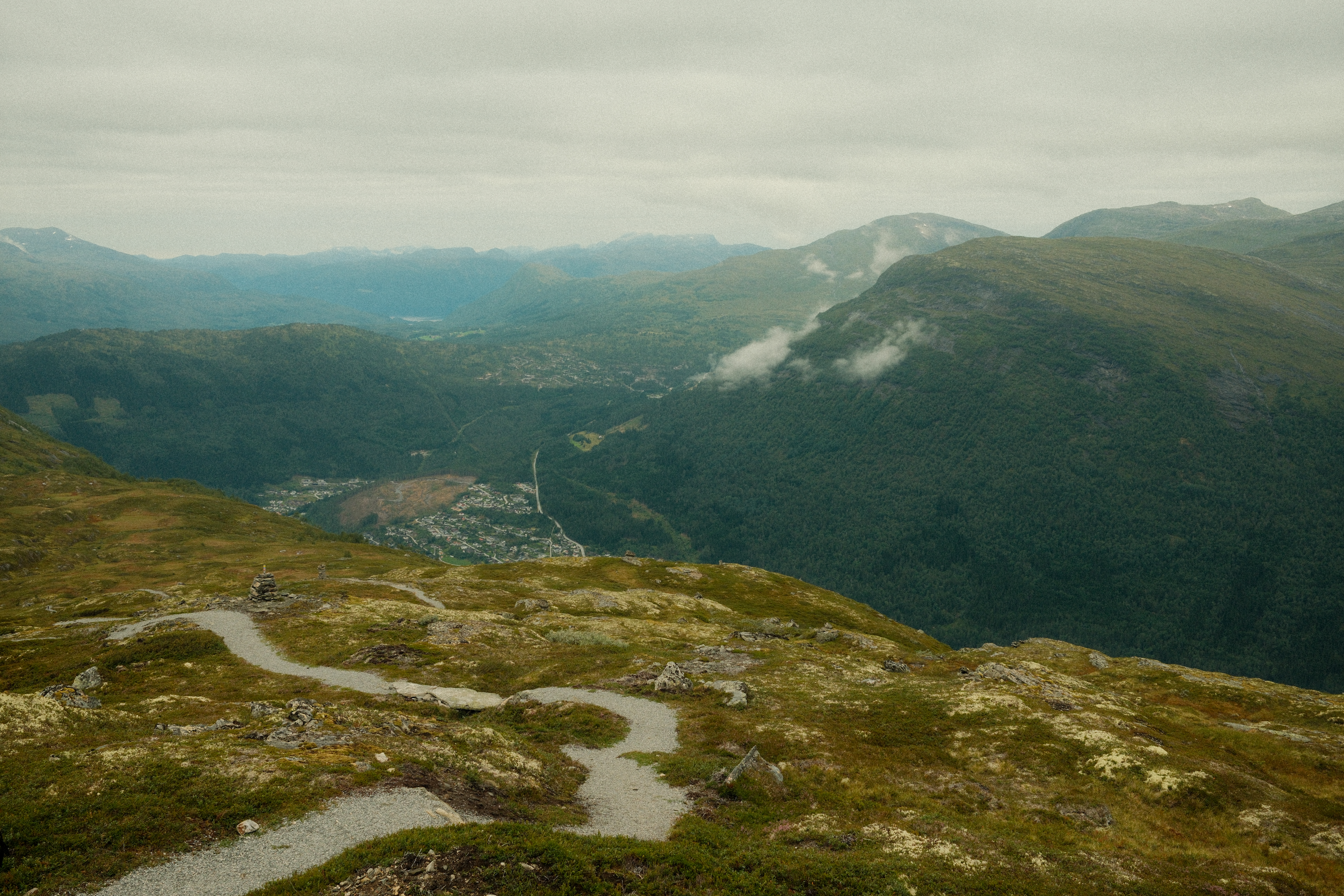A serene mountain landscape with misty clouds and a winding path.