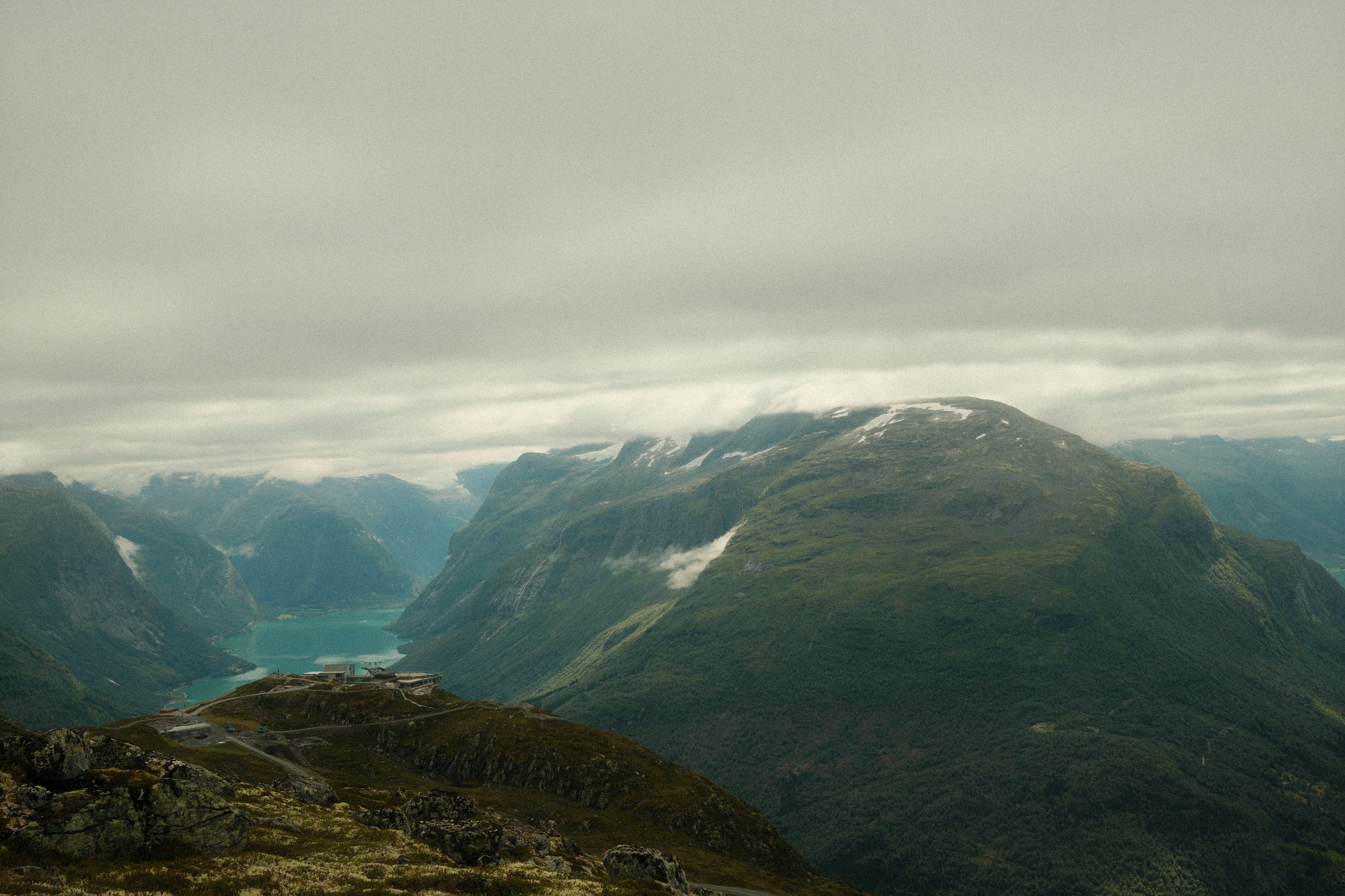 A panoramic view from the Loen Skylift in Norway, showing a vast fjord and surrounding mountains.