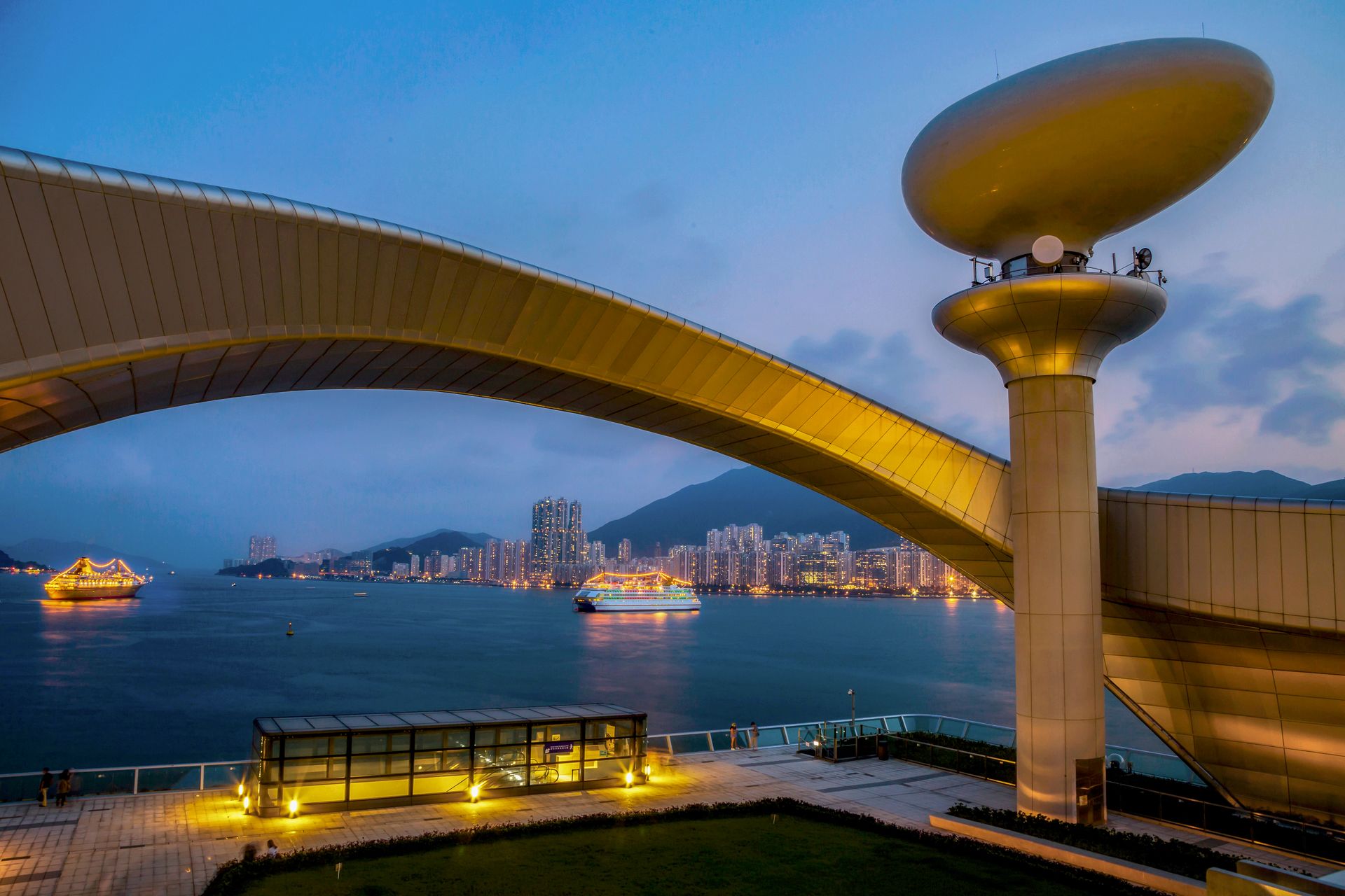 Stunning architecture overlooking Hong Kong Harbor at twilight, with illuminated buildings and cruise ships.