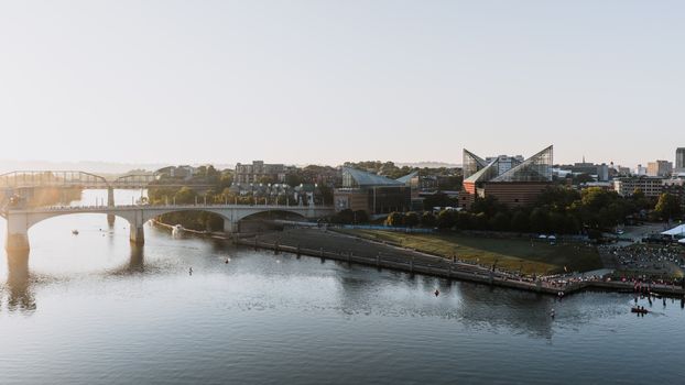 Scenic aerial view of Chattanooga's riverfront and bridges at sunset, showcasing city landmarks and waterfront activities.