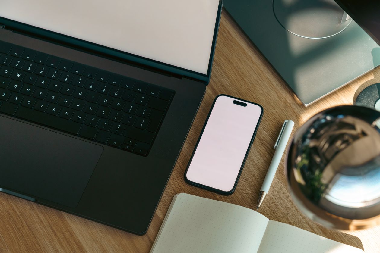 Aerial view of a modern workspace with laptop, smartphone, and notebook representing the AI tools side hustlers use in 2026