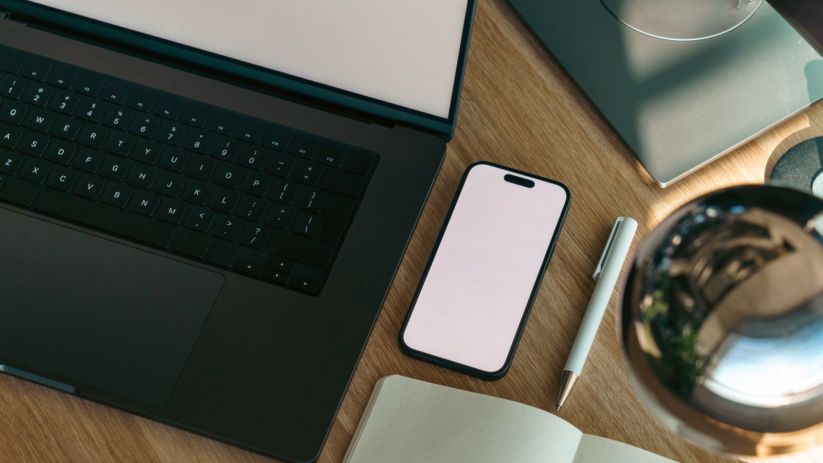 Top-down view of a laptop, smartphone and notebook arranged on a modern workspace