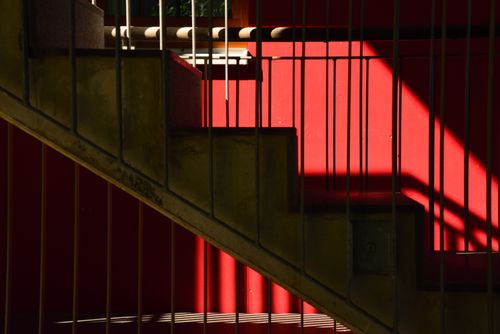 Free Concrete staircase with dramatic shadows against a vibrant red wall in Freiburg, Germany. Stock Photo