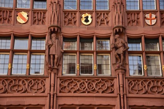 Ornate facade of historic building in Freiburg, featuring intricate stone carvings and emblems.