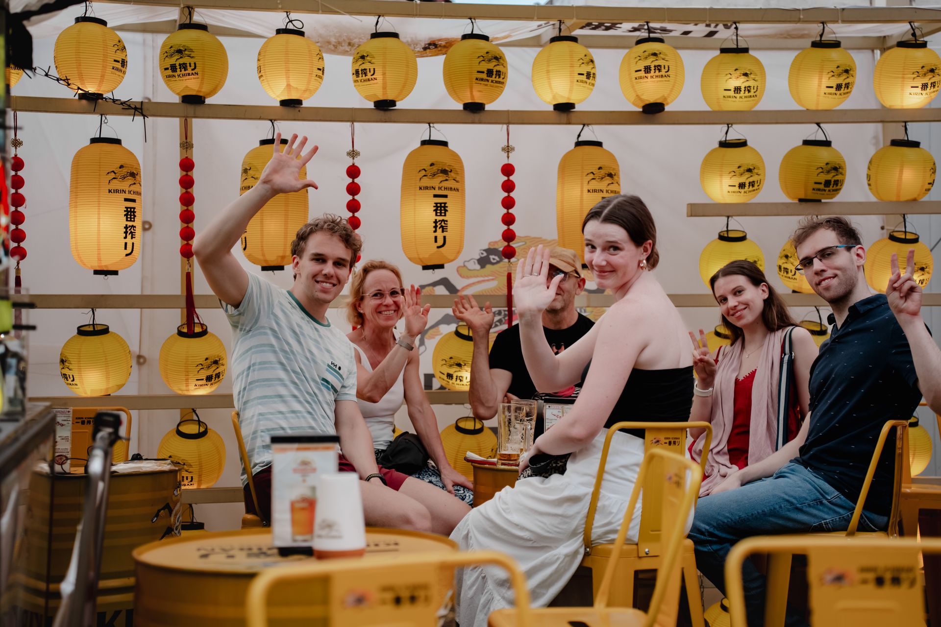 People sitting together with festive lanterns, enjoying a joyful gathering outdoors.