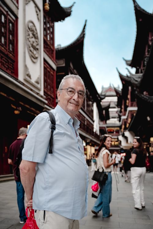 Free Elderly man touring a busy Asian market street with traditional architecture. Stock Photo