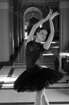 Graceful ballerina dancing in a classic hallway, monochrome elegance.