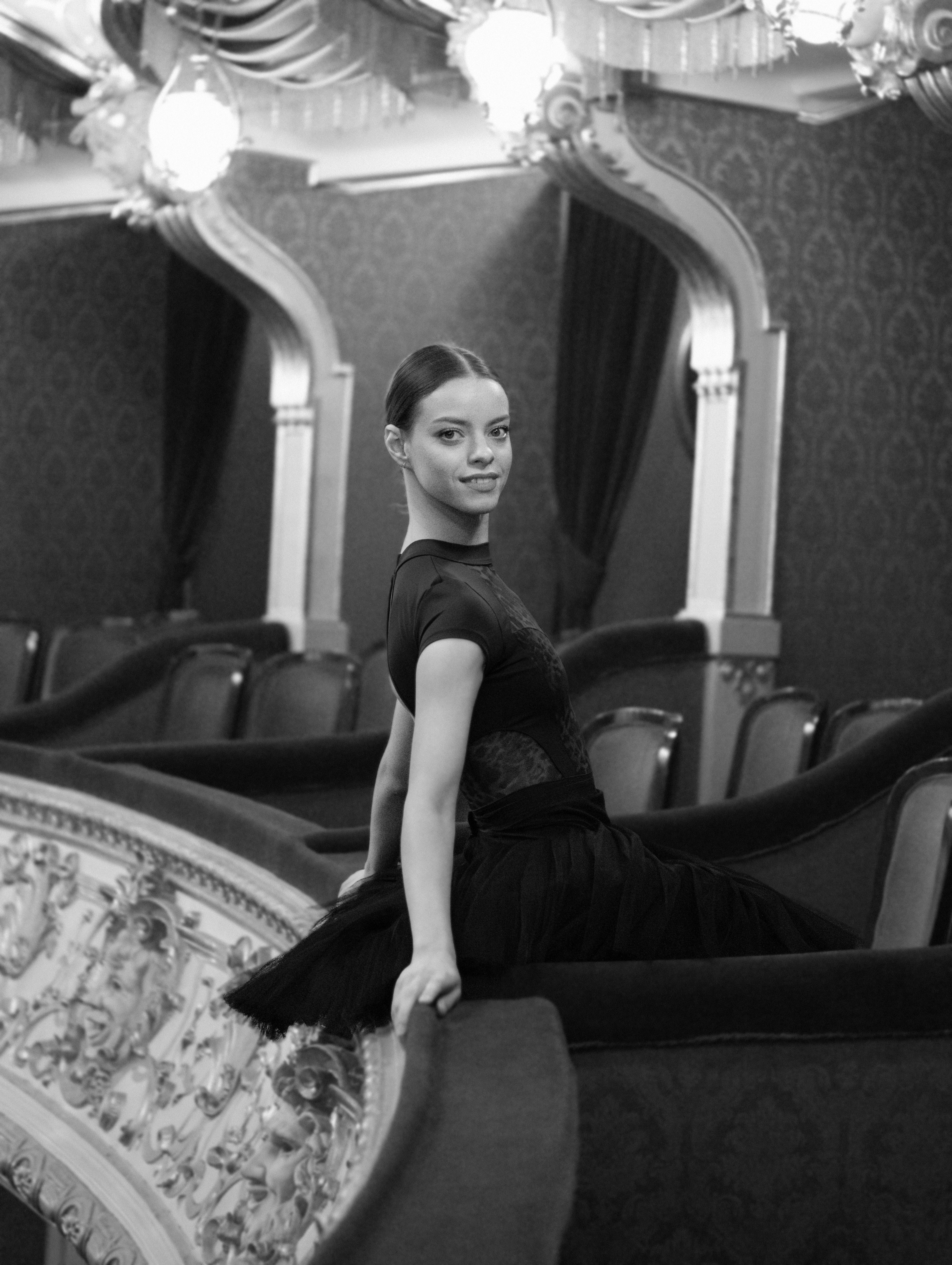 Ilmainen Balettitanssija poseeraa sulavasti vintage-teatteriympäristössä, mustavalkoinen valokuva. Kuvapankkikuva