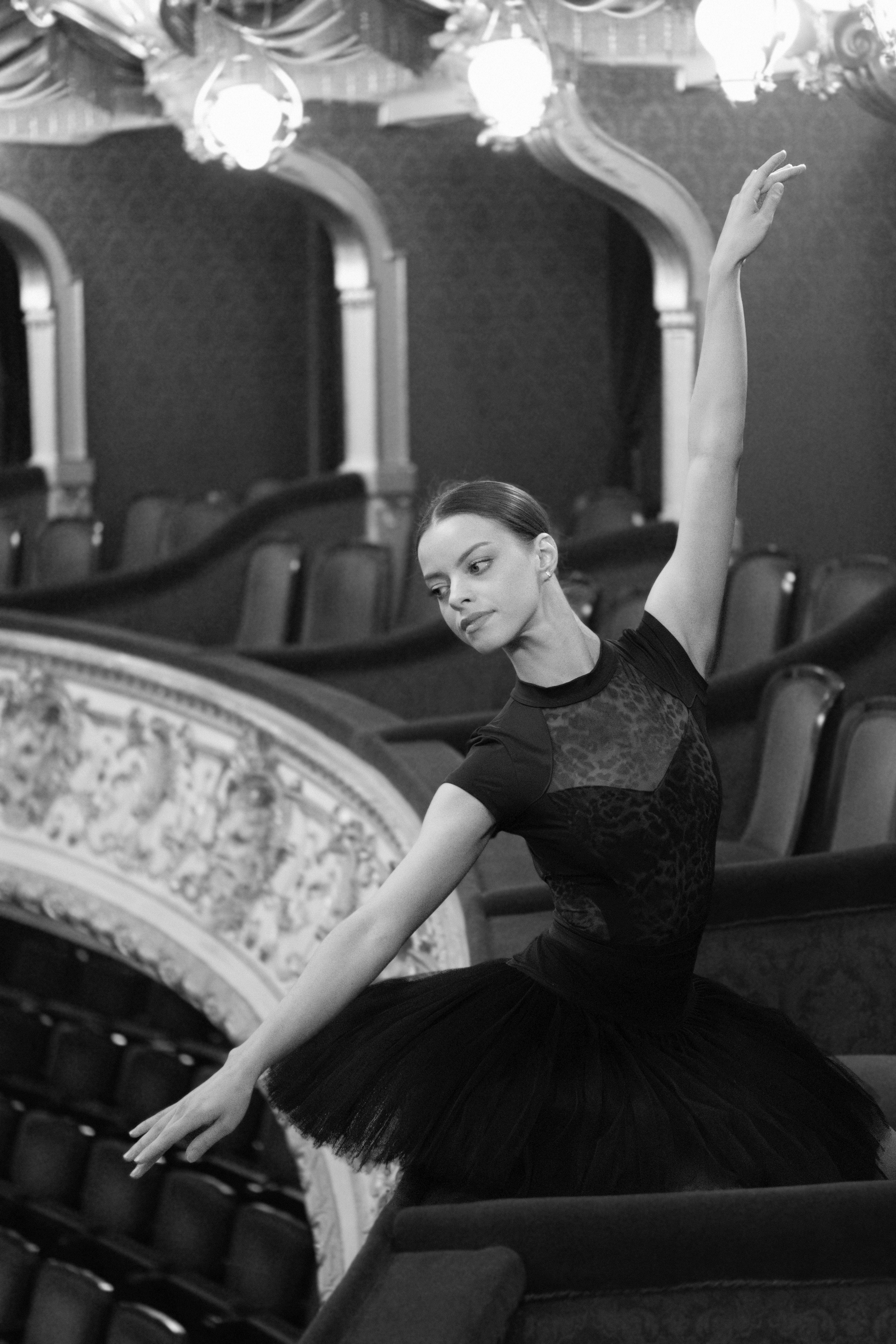 Free Ballerina in black tutu performing gracefully inside historic theater, capturing elegance and poise. Stock Photo
