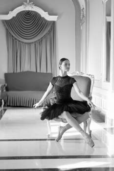 Graceful ballet dancer posing in a classic indoor setting with vintage decor.