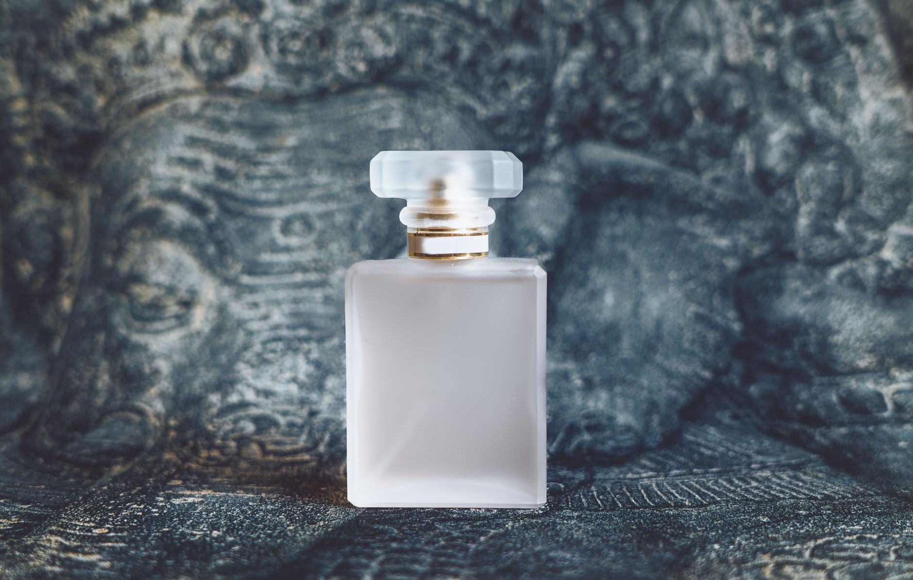 Minimalist square perfume bottle on textured artistic background capturing elegance and luxury.