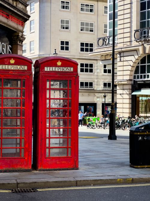 Free Capture of classic red telephone booths on a bustling London street, showcasing iconic architecture and vibrant city life. Stock Photo