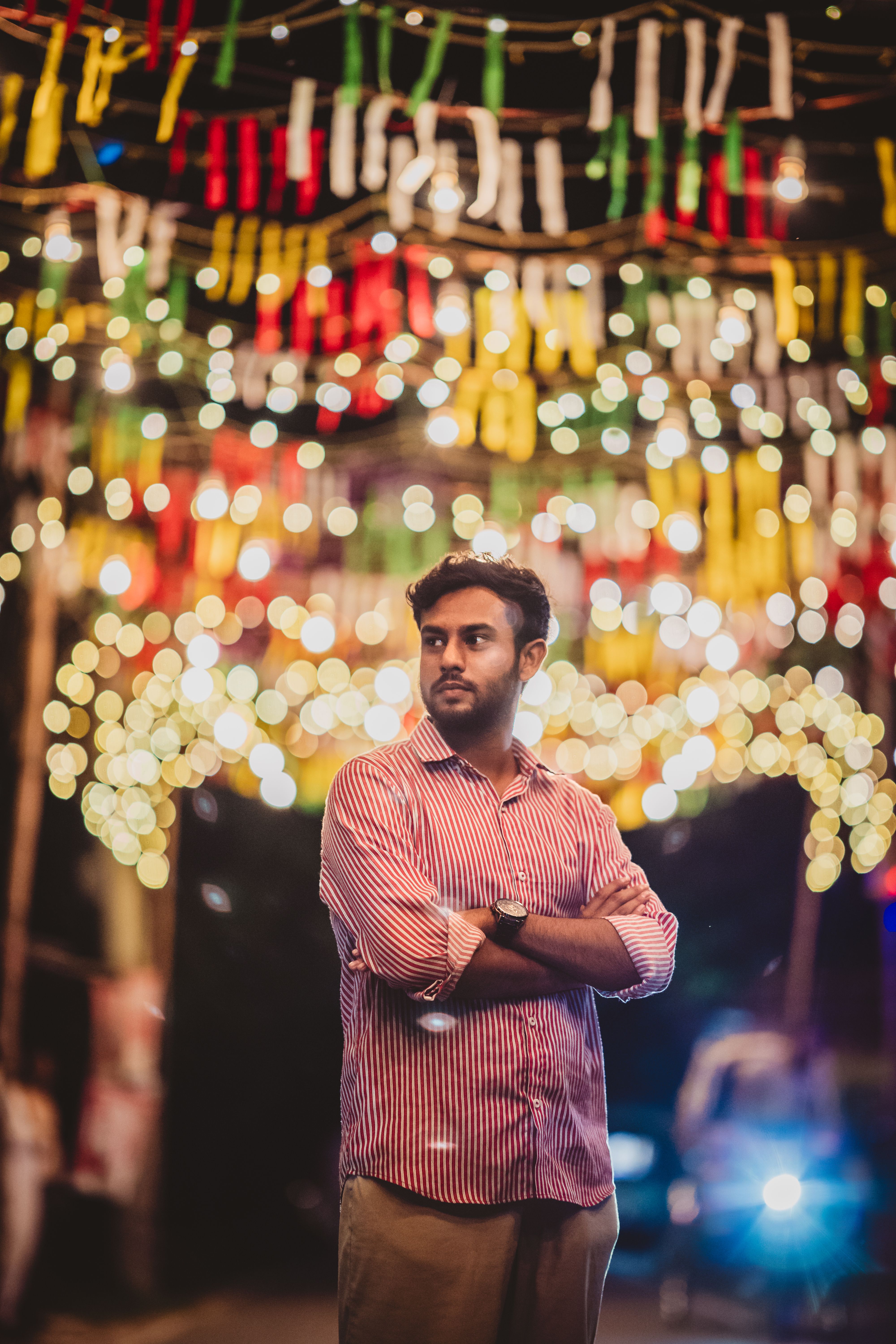 Portrait of a man surrounded by colorful festival lights in Faridpur, Bangladesh, showcasing a lively night scene.