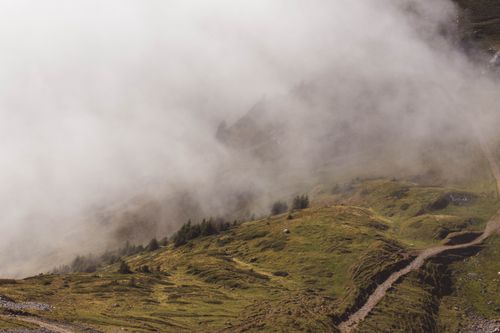 Free A serene view of fog rolling over the lush green hills of Alpnach, Switzerland. Stock Photo