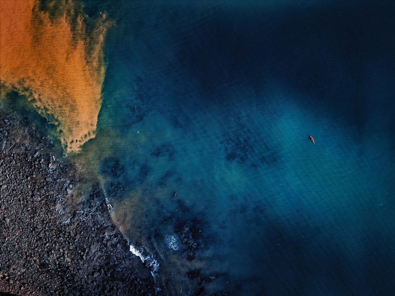 aerial shot of a lone kayaker paddling along the stunning sidmouth coa