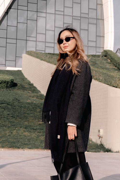 Free Fashionable woman in sunglasses stands confidently outdoors near a contemporary architectural design. Stock Photo