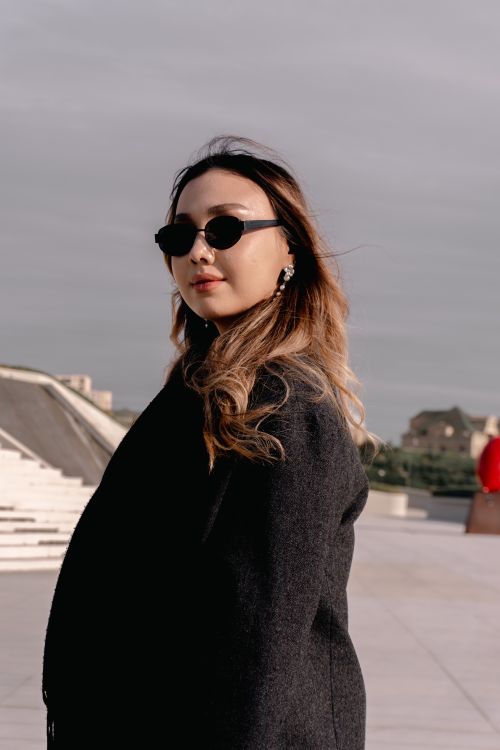 Free Chic young woman with sunglasses enjoying a sunny day outdoors, exuding confidence and style. Stock Photo