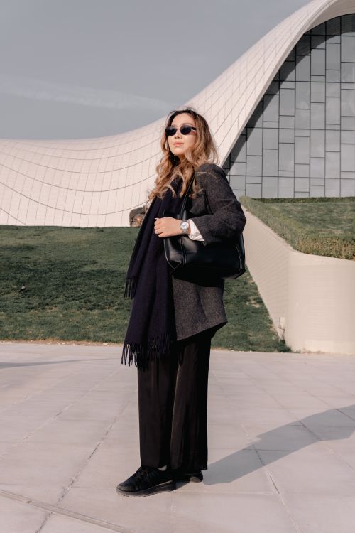 Free Fashionable woman with sunglasses poses by a modern architectural structure, exuding confidence and style. Stock Photo