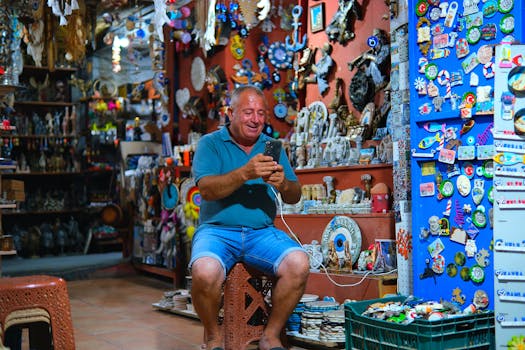 Cheerful man in a vibrant souvenir shop using his smartphone, surrounded by colorful trinkets.