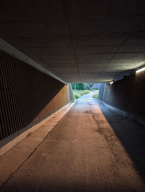 Free A tunnel in Geel, Belgium opening into a vibrant natural landscape during sunset. Stock Photo